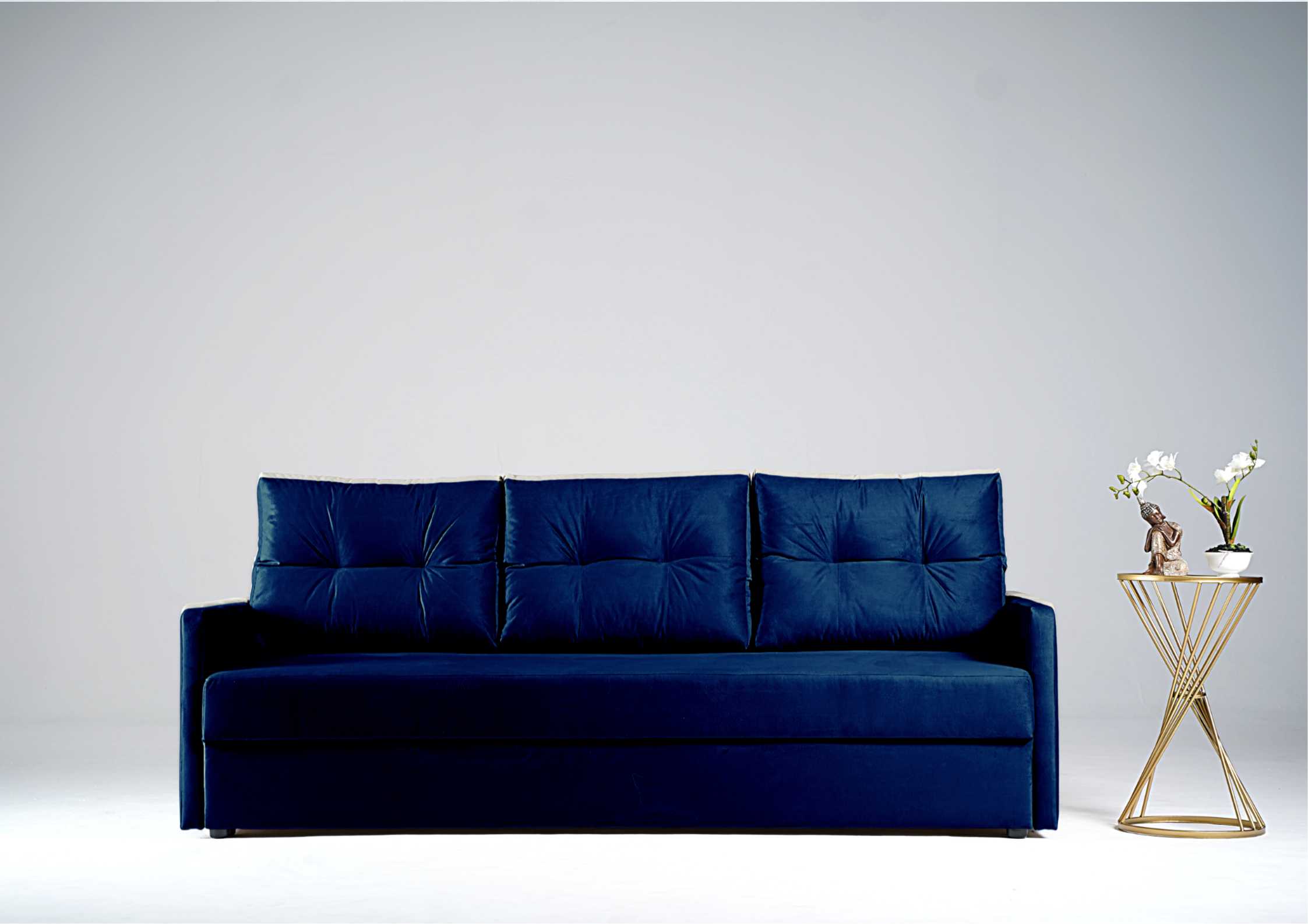 Granatowa sofa z pikowanymi poduszkami